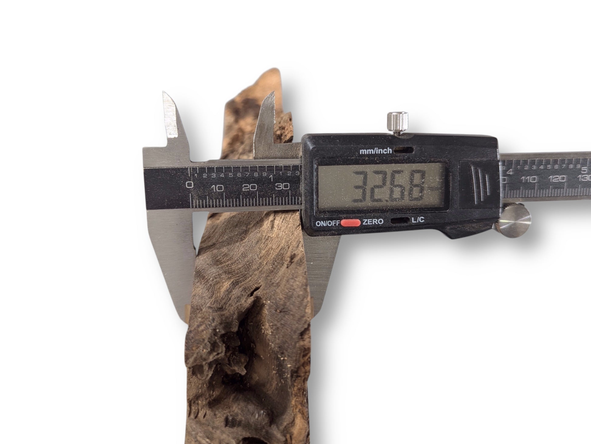 Digital caliper measuring an irregular, dark brown black locust root wood slice, showing a 32.68 mm thickness.