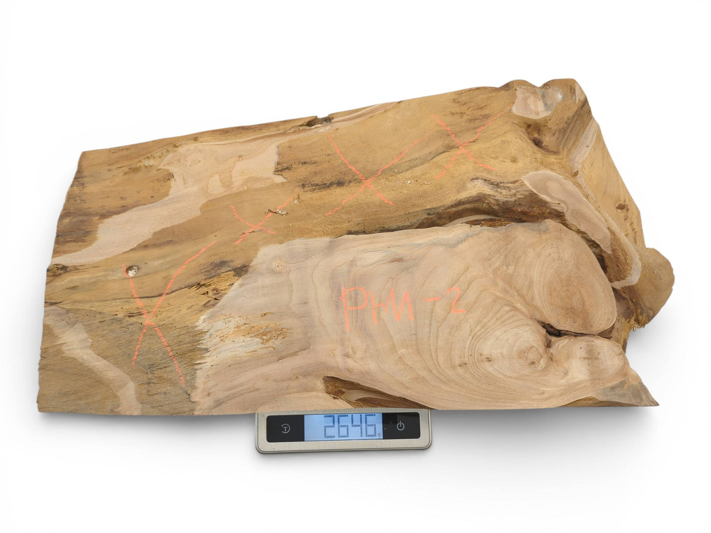 An unfinished piece of alder lumber with orange markings is positioned on a digital scale for weighing.