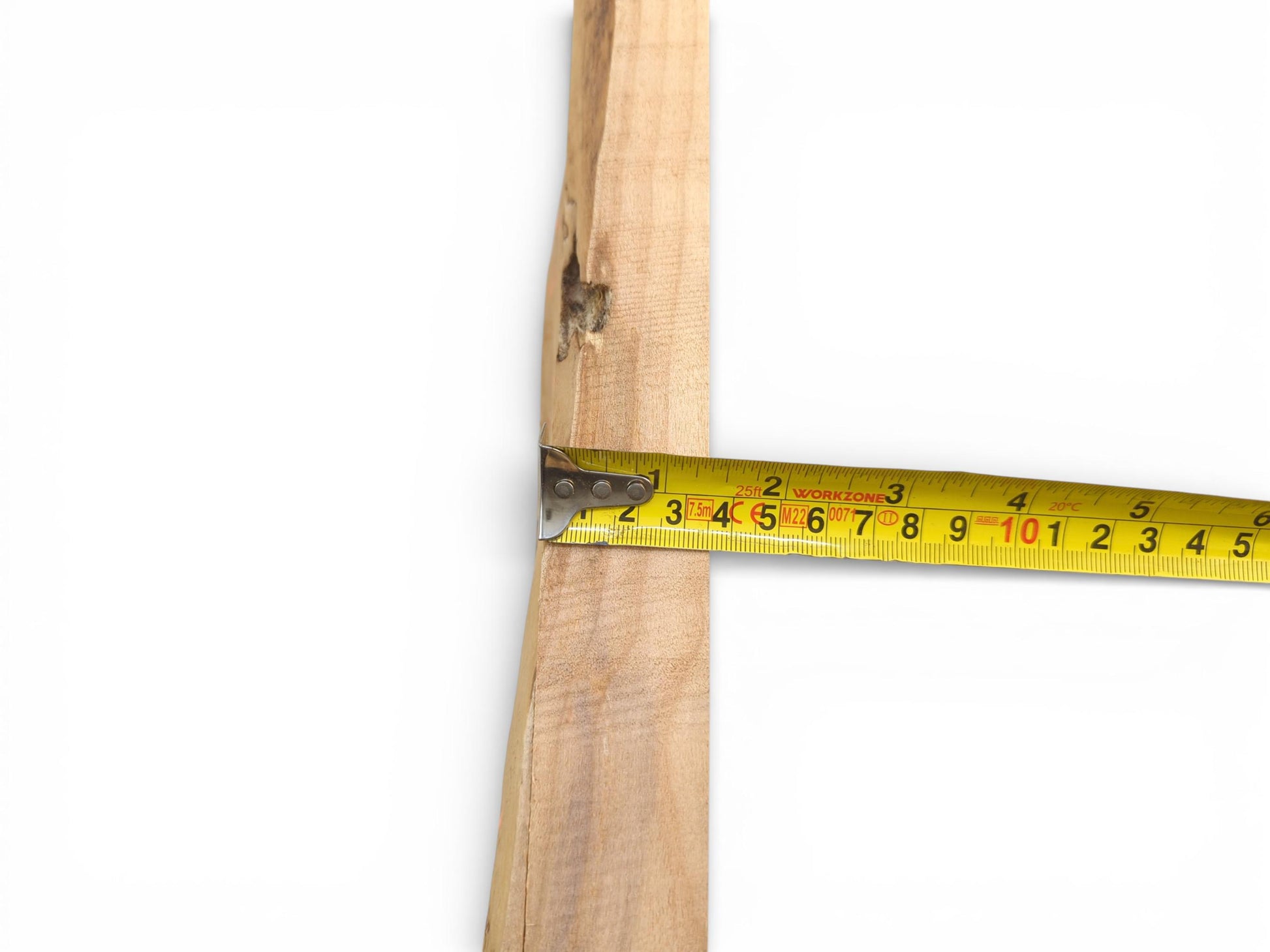 A horizontal yellow measuring tape is shown extended across a raw alder wood plank for sizing.