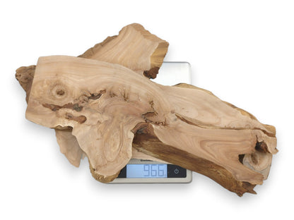 Two raw-edged timber blanks with prominent knots are weighed on a digital kitchen scale.