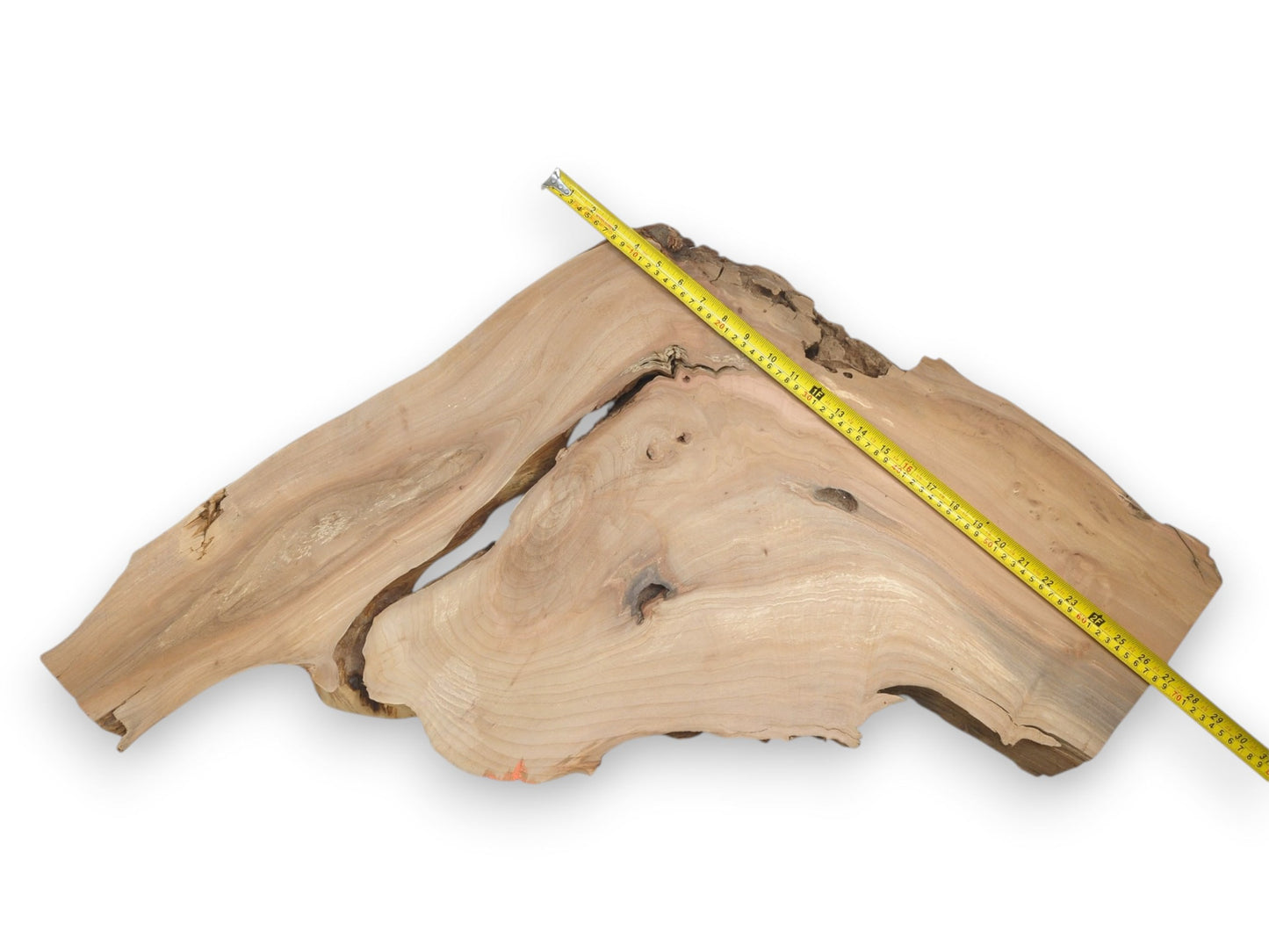 A yellow measuring tape stretches across a pale timber slab with an irregular, split shape.