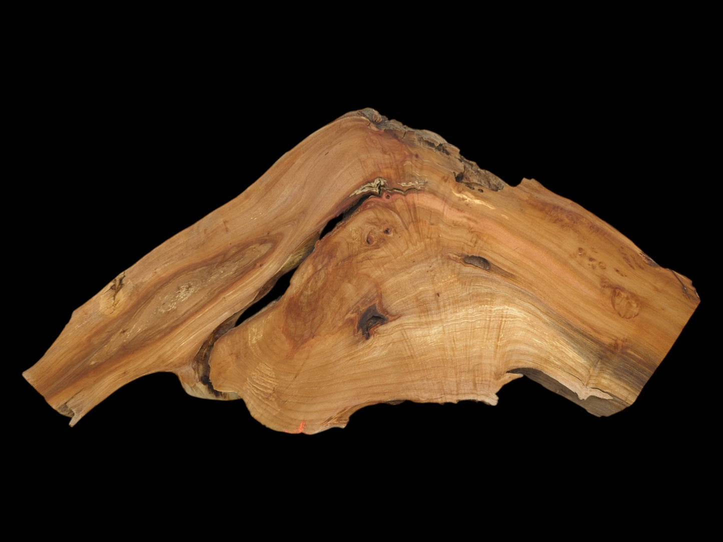 A deep crevice splits this mountain-shaped lumber, revealing flowing grain patterns and dark, embedded knots.