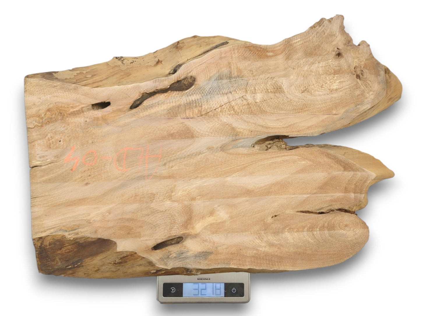 A wide, split piece of lumber with orange chalk marks rests on a scale.