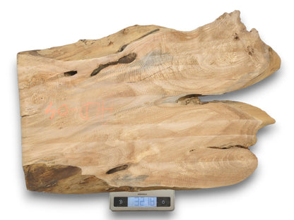 A wide, split piece of lumber with orange chalk marks rests on a scale.