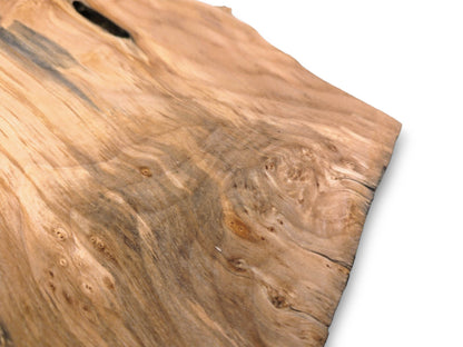 A timber piece shows grey mineral stains flowing through swirling burl patterns and small knots.