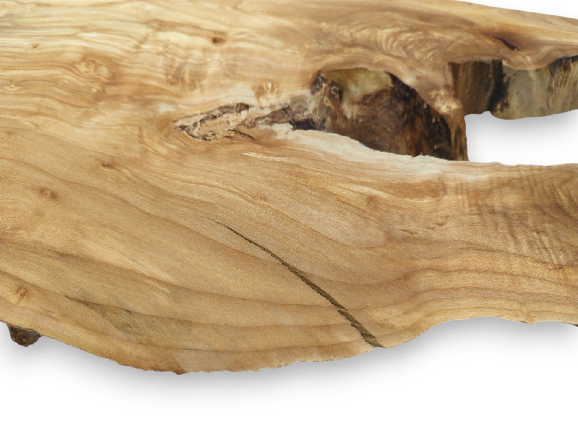 Flowing, golden grain surrounds a dark, rough-textured hollow in a piece of lumber.