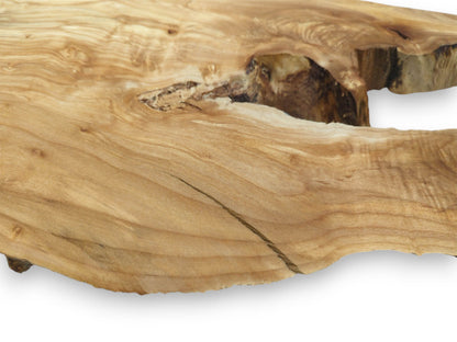 Flowing, golden grain surrounds a dark, rough-textured hollow in a piece of lumber.
