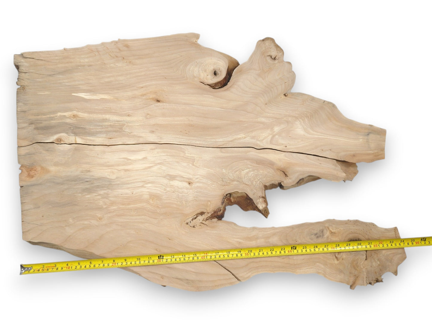 A measuring tape spans an irregular timber slab split by a long, dark horizontal crack.