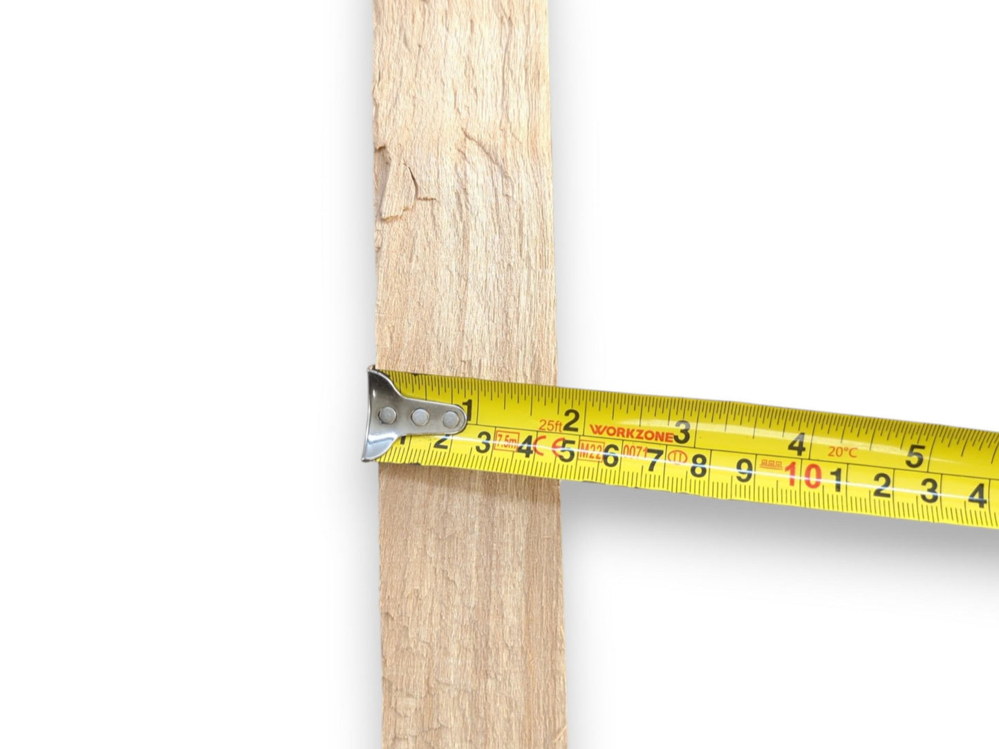 A yellow tape measure gauges the width of a vertical, rough-sawn plank of wood.