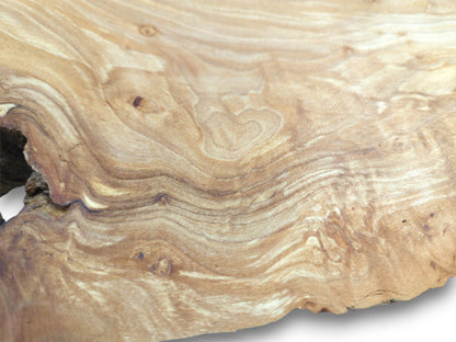 A polished timber surface shows a natural heart shape formed by its flowing, contoured grain.