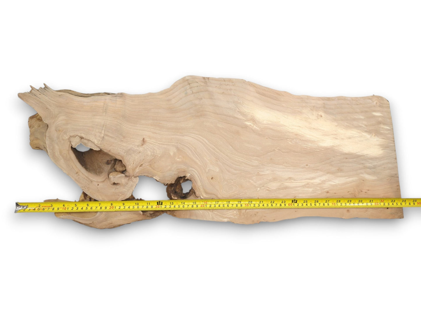 A pale, elongated timber slab displays sweeping grain around a large, hollowed-out knot.