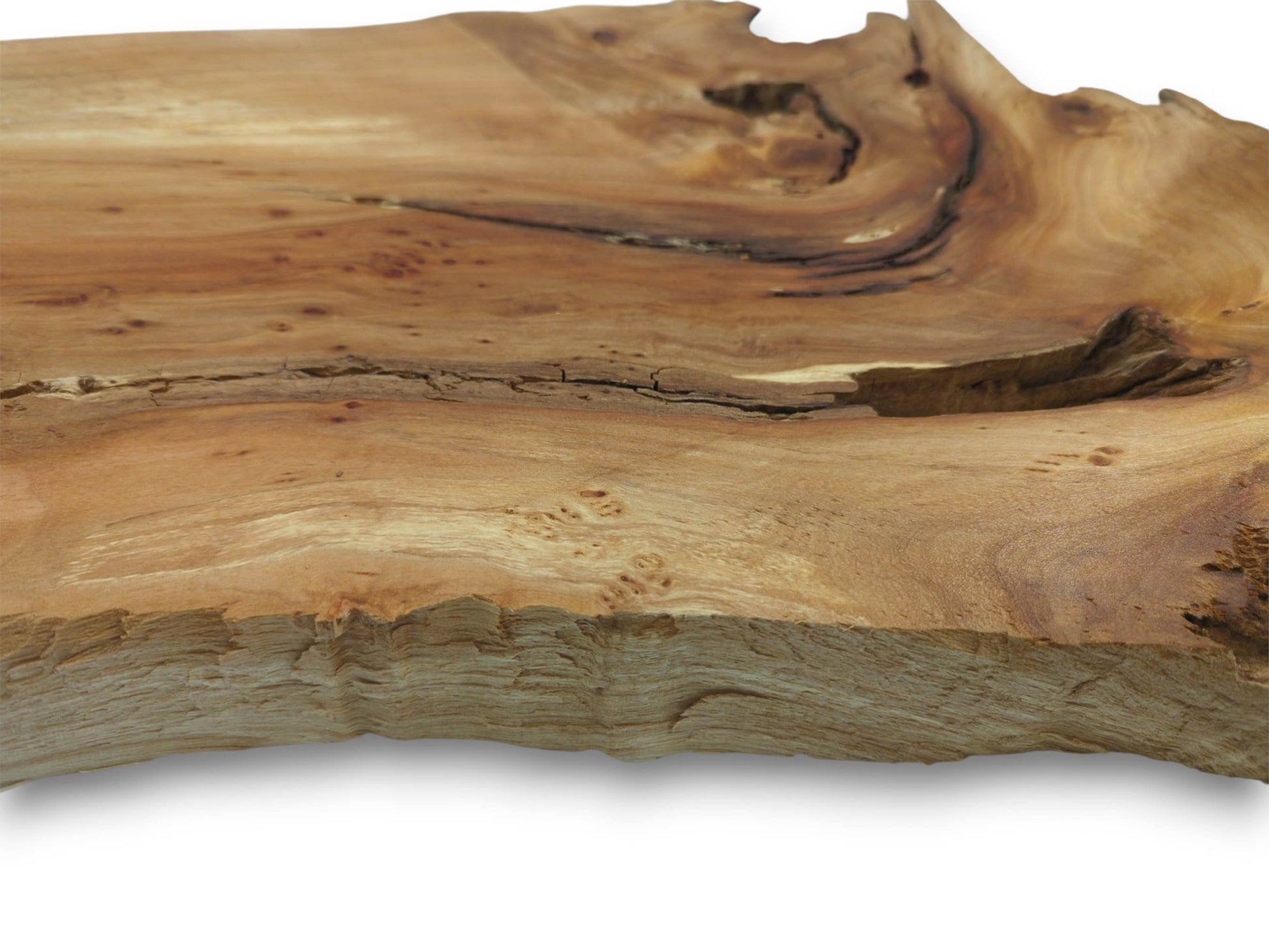 A low-angle view of a timber slab with a swirling grain, dark fissure, and splintered edge.