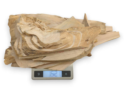 A pile of light-colored alder wood pieces with natural edges on a digital scale.