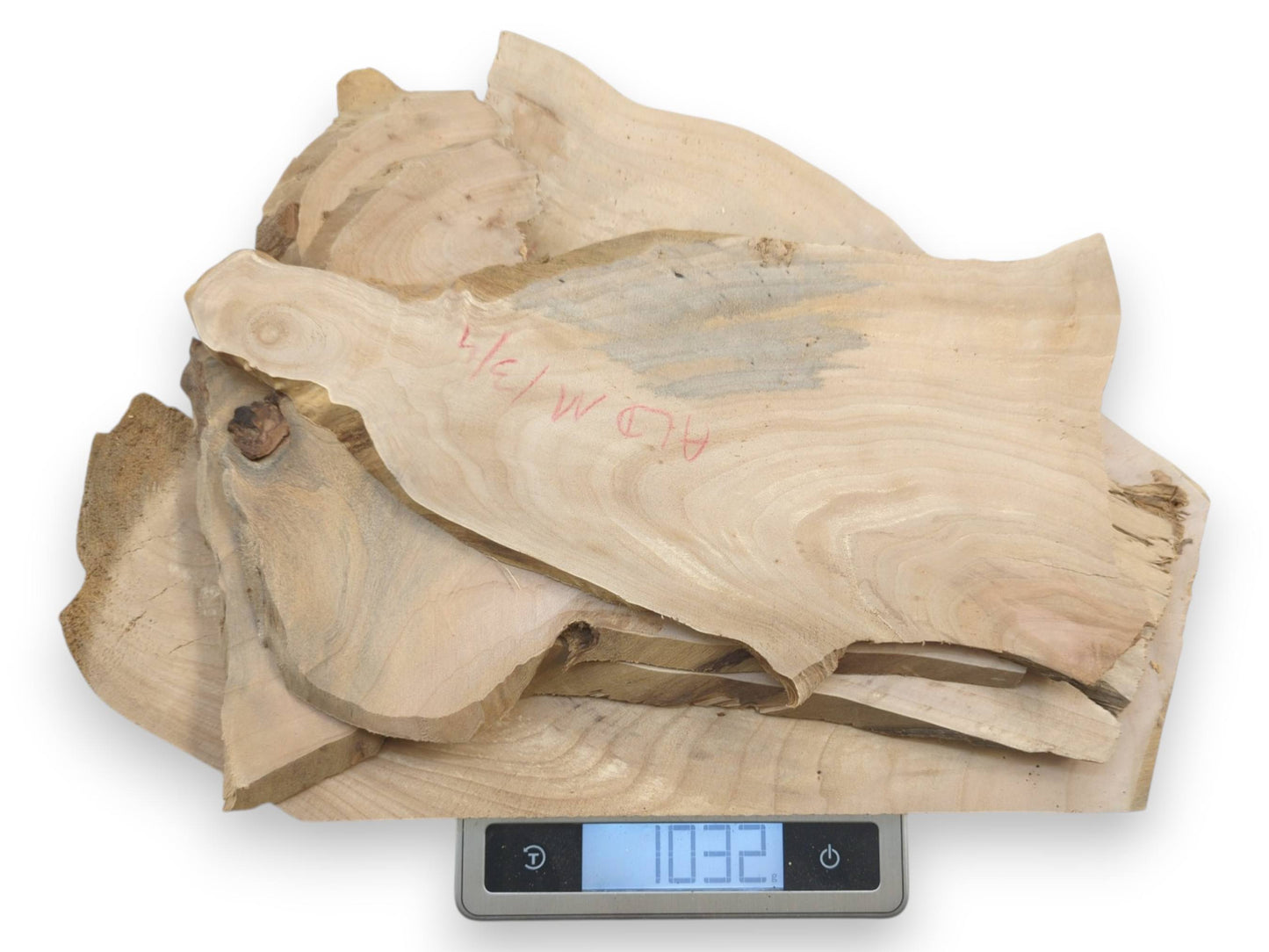 A stack of light-colored, thin alder wood slices with natural live edges on a scale.