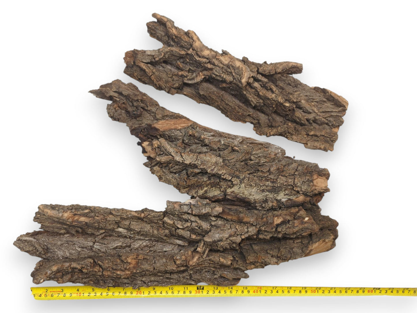 Two large pieces of rugged brown bark are arranged together above a yellow tape measure for scale.