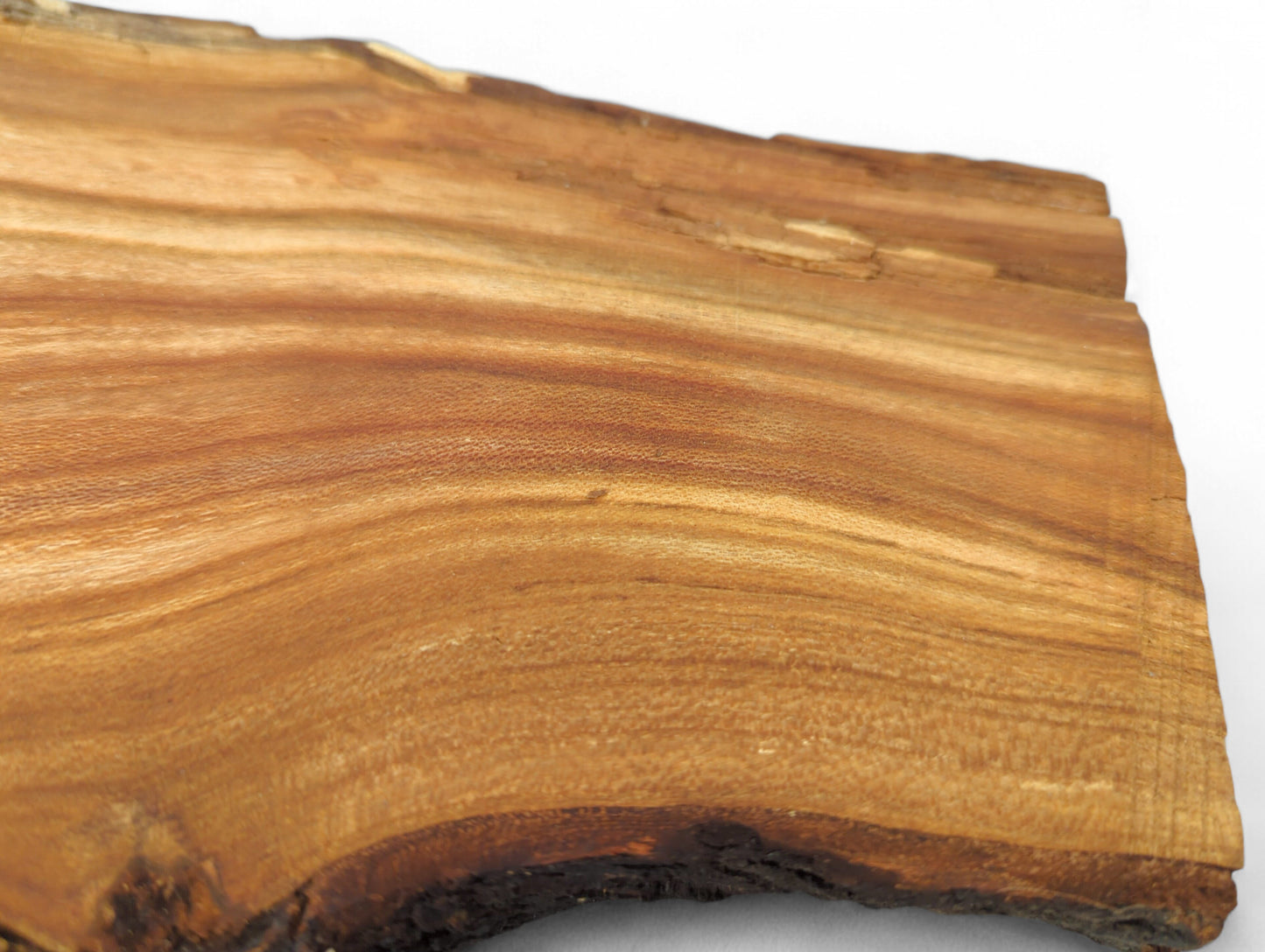 Rustic wood slice with light reddish-brown color, distinct wavy grain, and a dark, textured live edge.