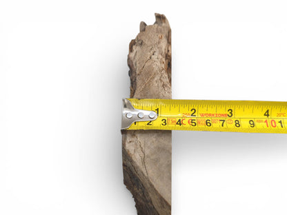 A close-up of a tape measure held against the slab's profile to verify its thickness.