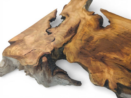 A perspective shot focusing on the knotted burls and weathered, uncut border of a cherry slab.