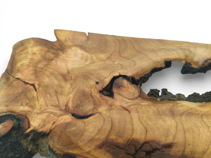 Detail of a cherry wood slab's surface, showing grain contouring around a dark, hollow knot.