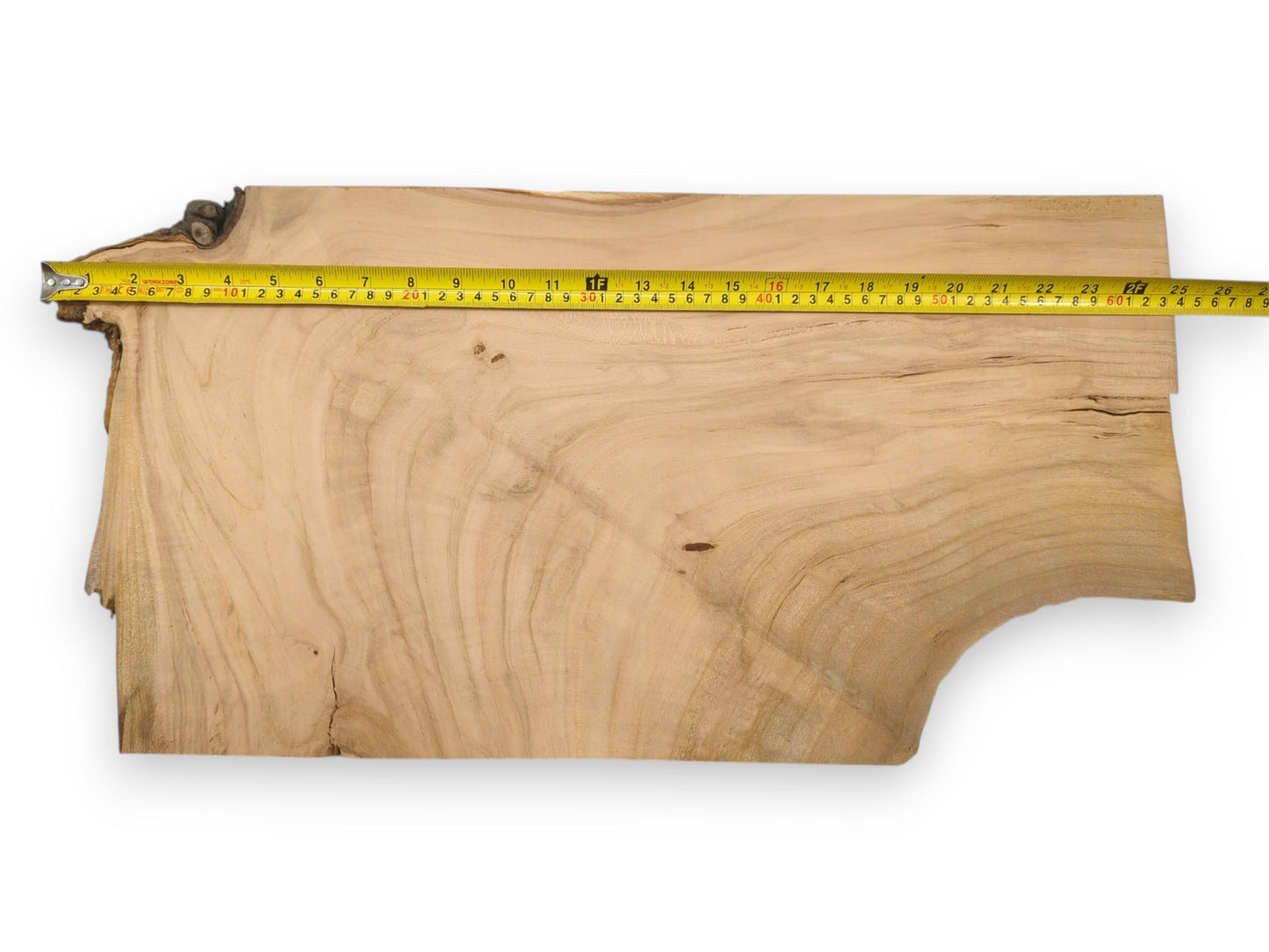 An overhead view of a live edge cherry lumber blank with a tape measure along its length.