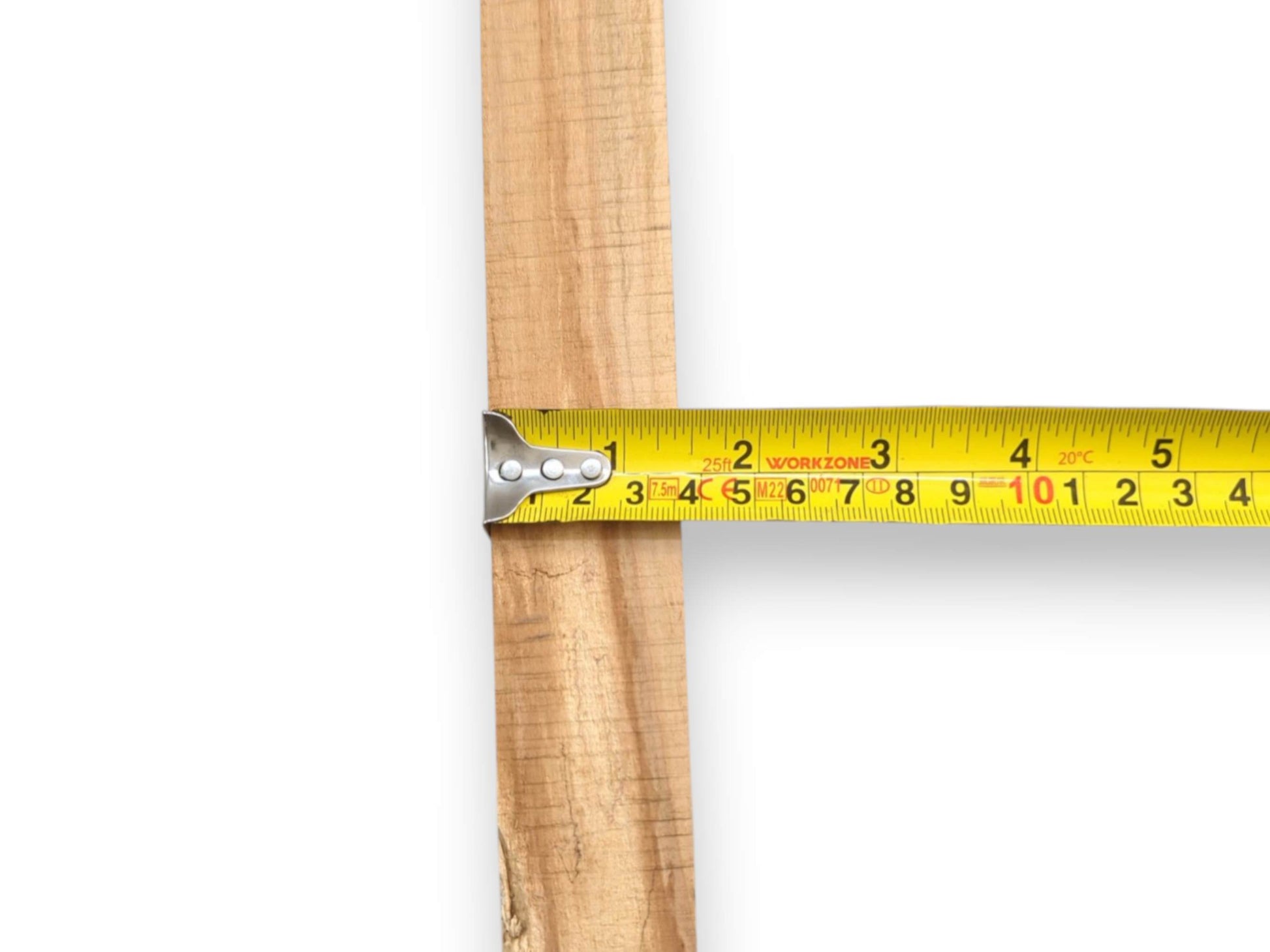 A yellow tape measure is positioned horizontally to indicate the precise width of a cherry plank.