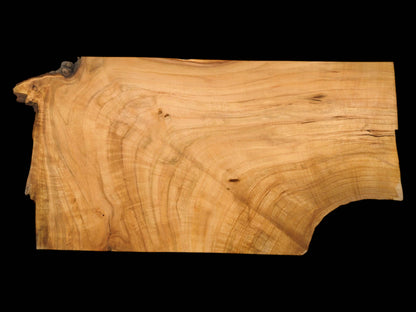 Overhead view of a wild cherry slab featuring a wavy, golden-brown grain and a dark, natural edge.