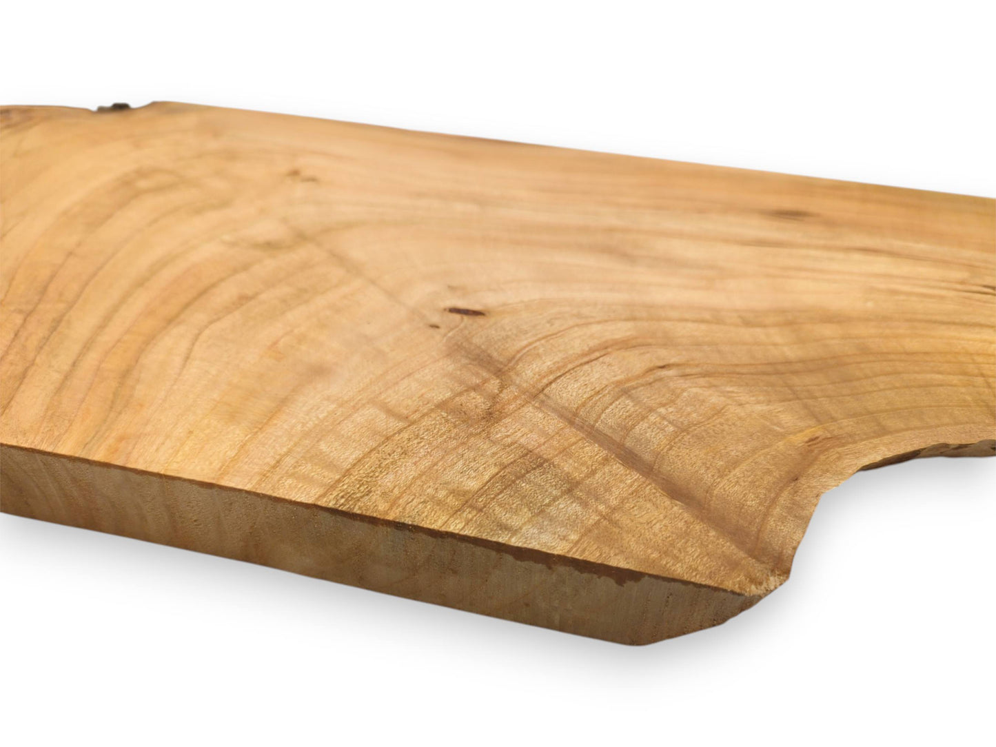 A close, low-angle perspective of a light cherry wood slab highlighting its undulating grain and thickness.