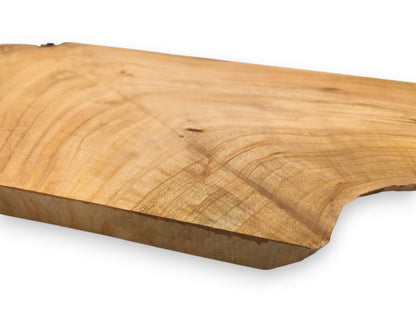 A close, low-angle perspective of a light cherry wood slab highlighting its undulating grain and thickness.