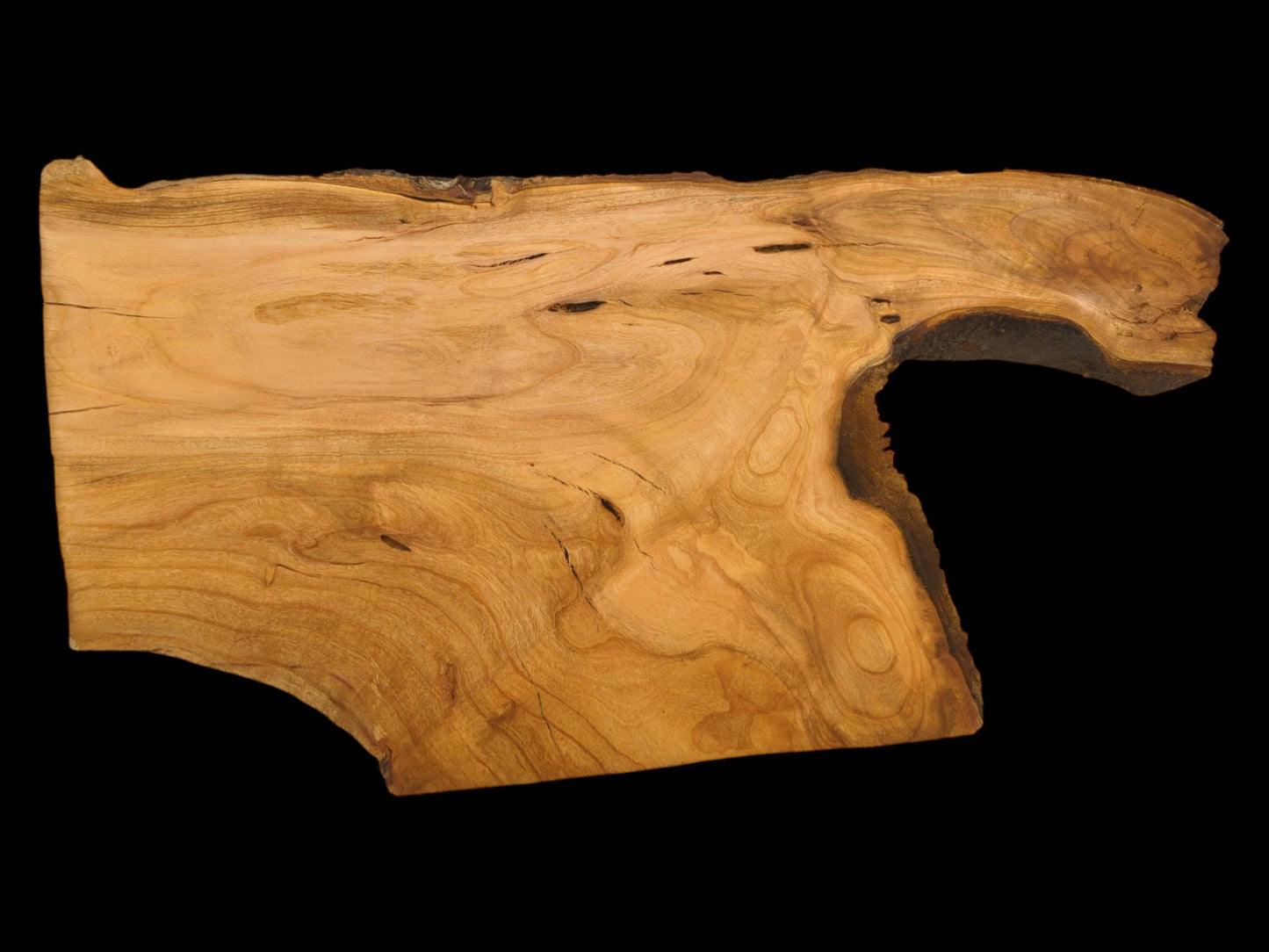 An overhead photograph of an irregularly shaped cherry slab featuring prominent, swirling grain and a deep curve.