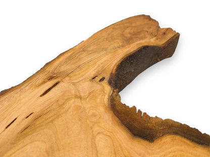 A focused look at a cherry slab's corner, showing the wood figuring and dark, organic contour.