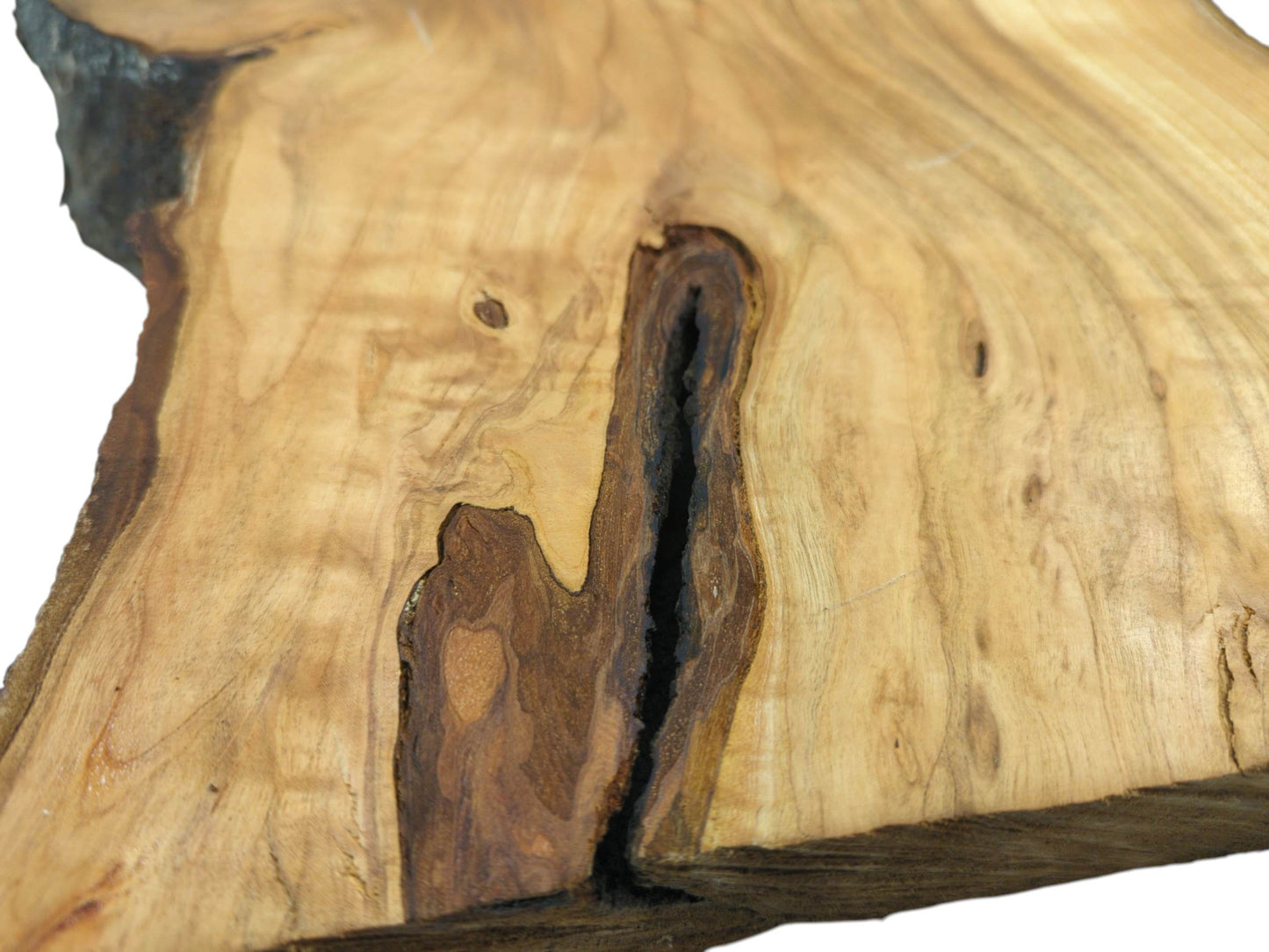 A tight shot of a cherry wood slab, detailing a deep, dark, bark-lined cavity within the grain.