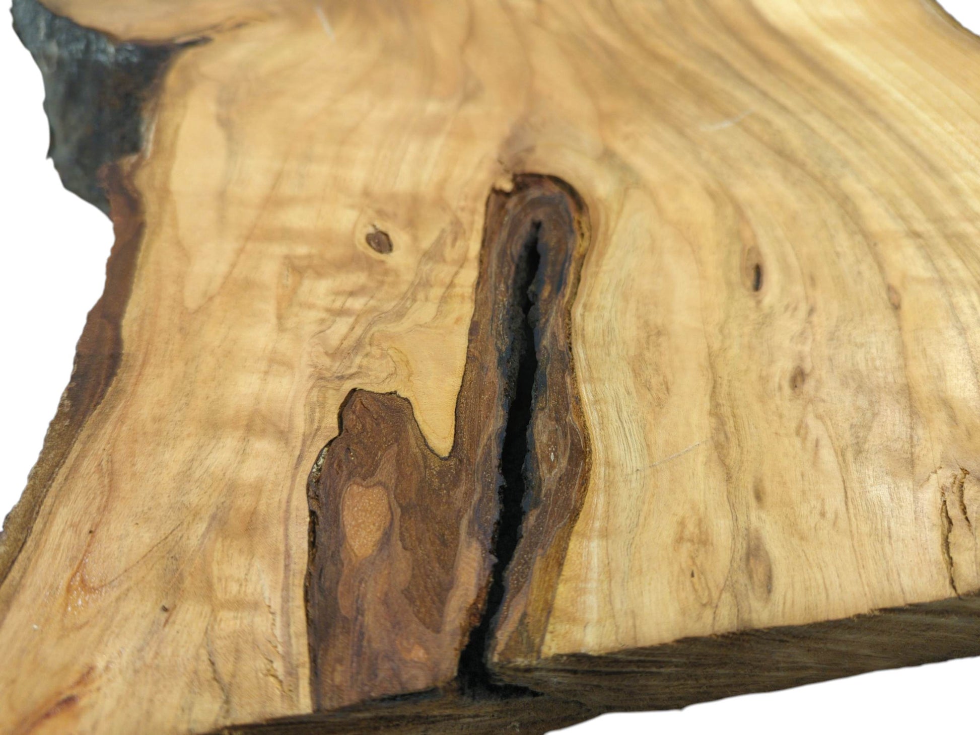 A tight shot of a cherry wood slab, detailing a deep, dark, bark-lined cavity within the grain.