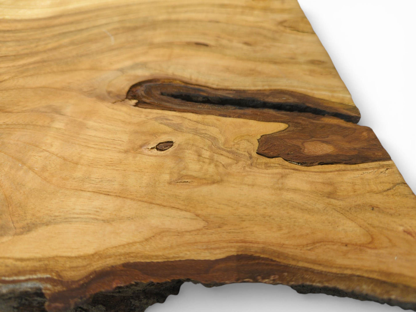 A raw cherry timber slab displaying its wavy, light grain around a dark, hollowed-out knot.
