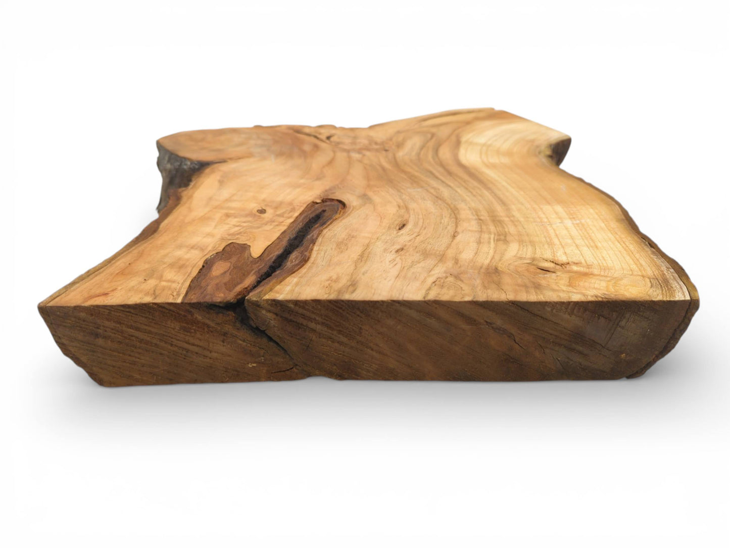 Eye-level perspective of a thick, unfinished cherry slab, displaying its end grain and a dark fissure.