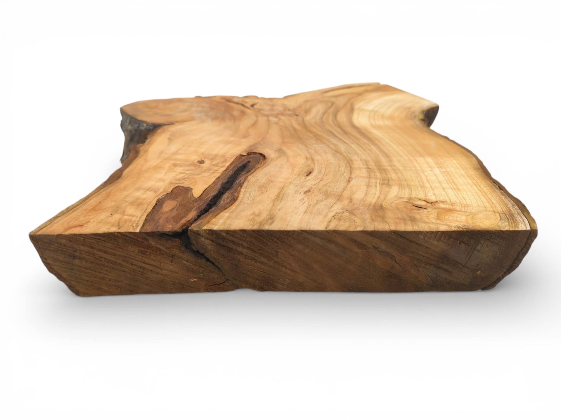 Eye-level perspective of a thick, unfinished cherry slab, displaying its end grain and a dark fissure.