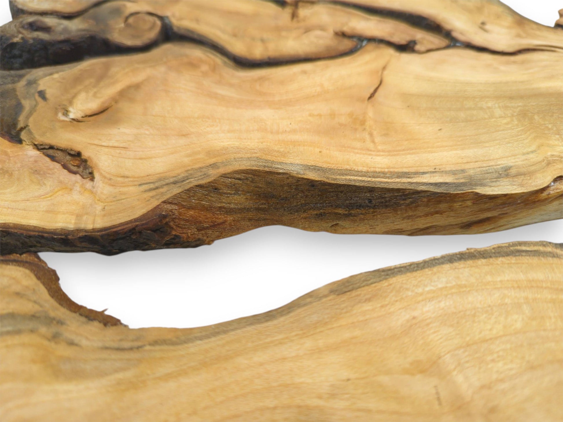 An extreme close-up on the undulating live edges and swirling grain of two cherry root sections.