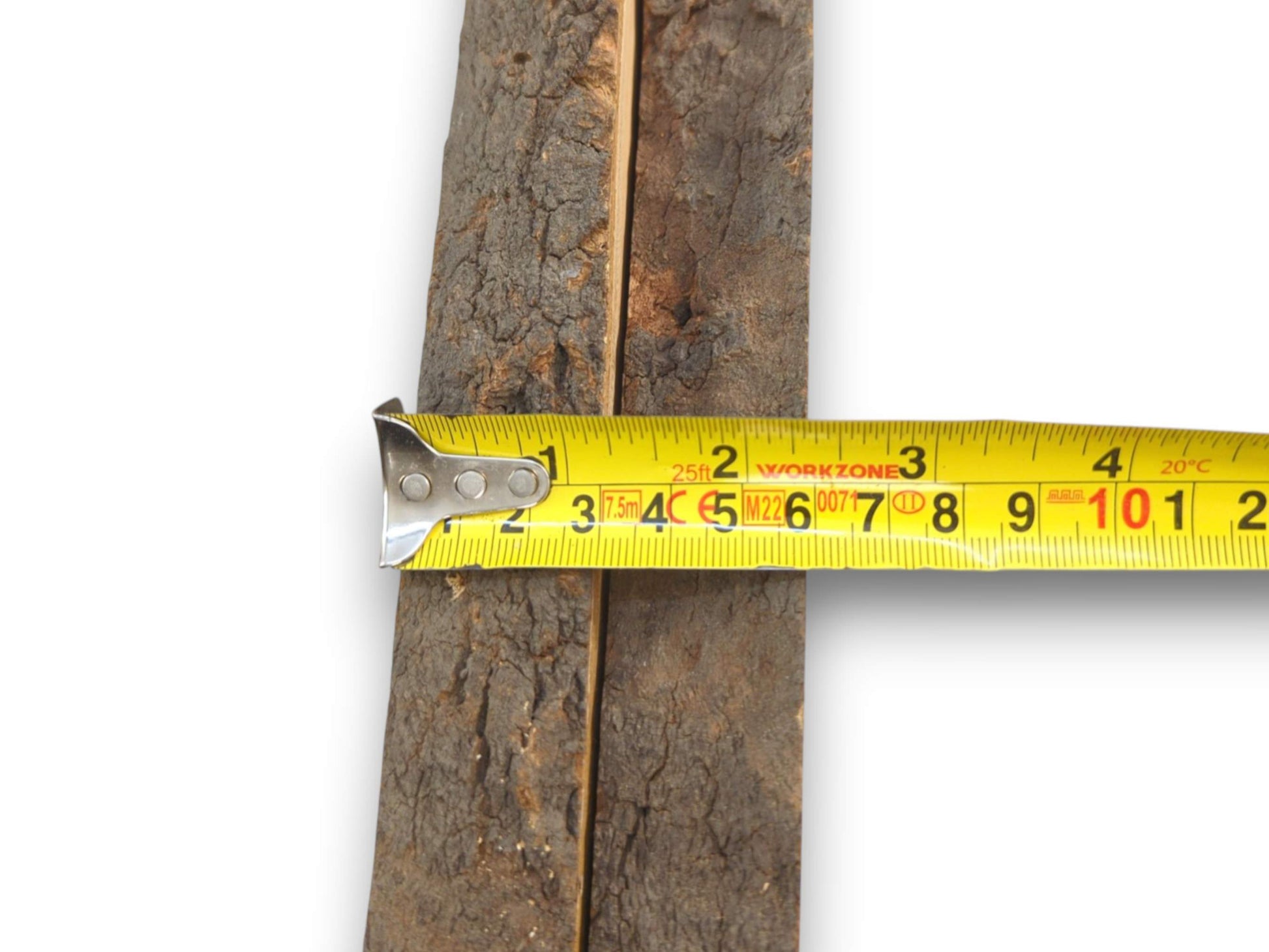A yellow measuring tape is stretched horizontally across two wood slabs, displaying their combined width.