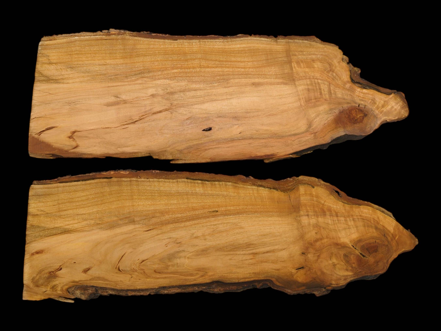 A pair of wild cherry live-edge wood slabs are photographed from above against a dark surface.