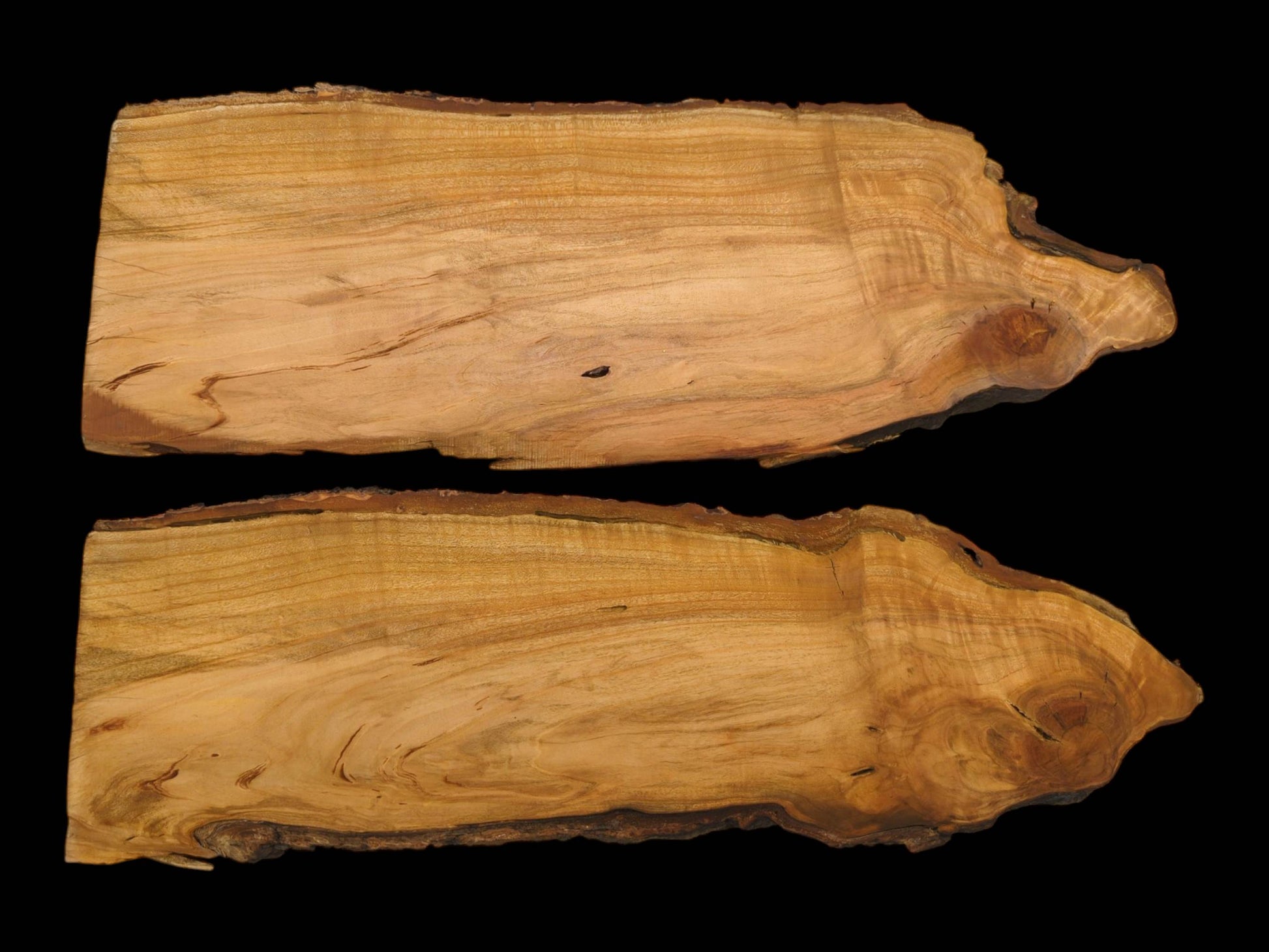 A pair of wild cherry live-edge wood slabs are photographed from above against a dark surface.