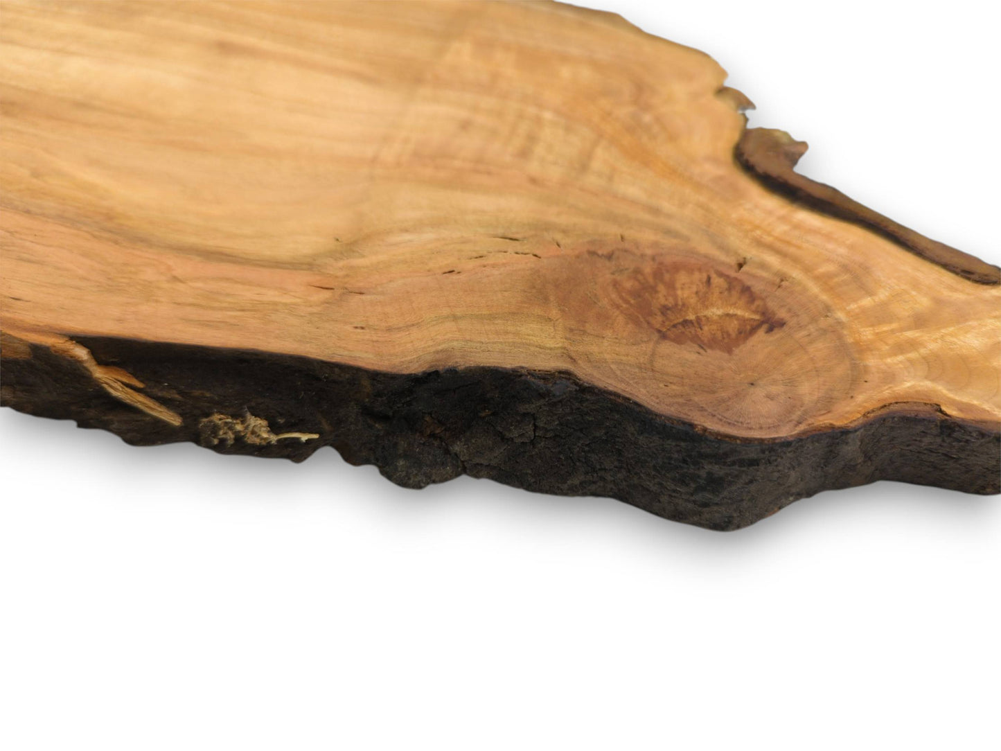 An angled, close-up photograph of a wood slab's textured, dark live edge and smooth, knotted surface.