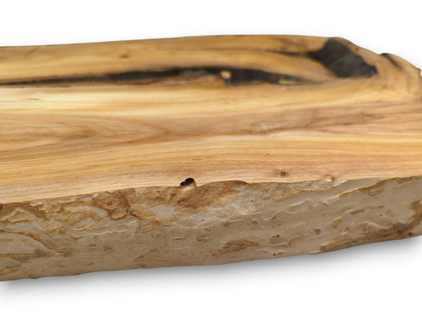 A macro view of a cherry wood slab's edge, detailing the intricate, carved-like texture and voids.