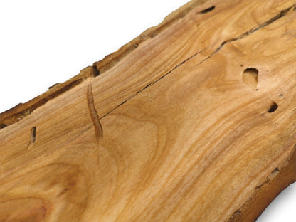 An angled perspective on a cherry wood surface, featuring its grain, a central fissure, and small holes.