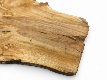 A close view of the slab’s corner, showing the light brown surface grain and splintered live edge.