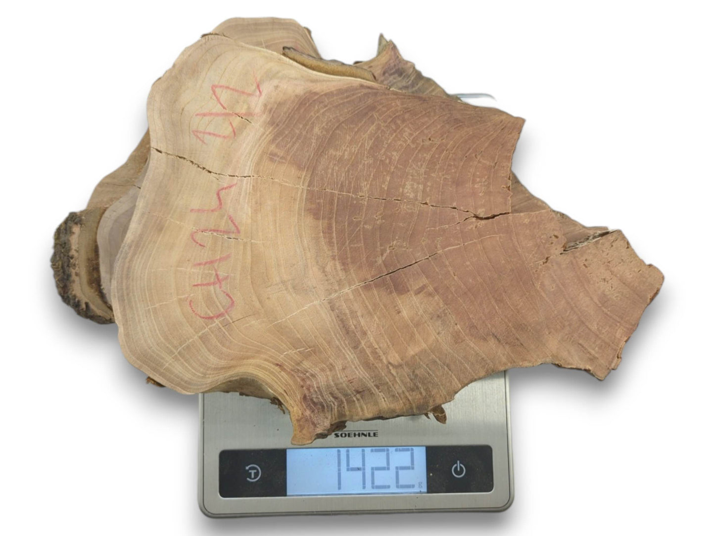 A light brown cherry wood slab with live edges and visible cracks on a scale.