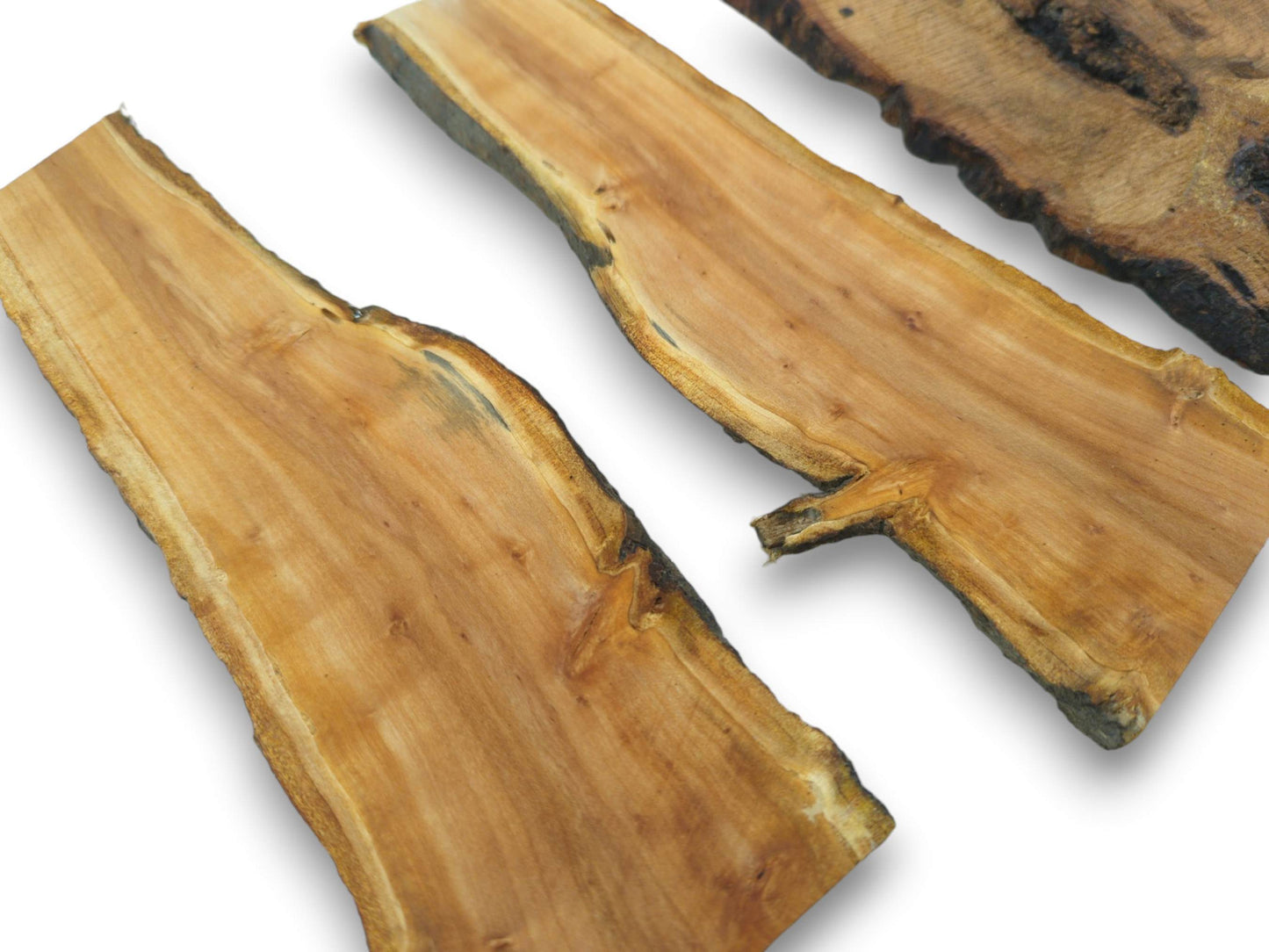 Three cherry wood slices with live edges and visible grain, one with a small branch.