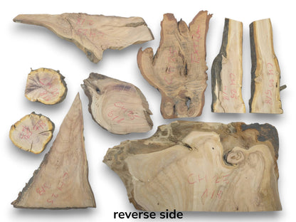 An overhead view of nine varied cherry wood pieces with live edges and natural grain.