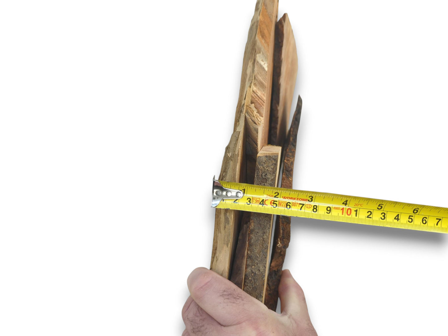 A hand holds multiple cherry wood pieces, measured by a yellow tape against a white background.