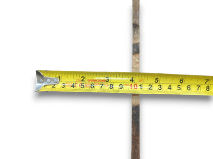 A yellow tape measure crosses a thin, rough-barked cherry wood piece on a white background.