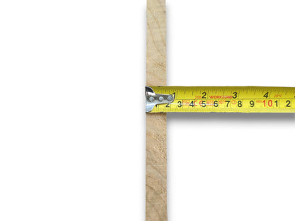 A yellow tape measure against a thin, light-colored wood piece with a rough edge.