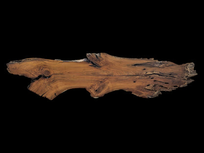 A long, live edge cherry wood slab with natural curves, visible knots, and holes.
